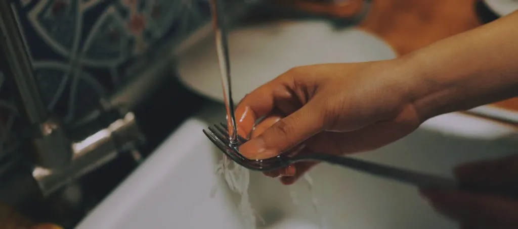 Gabel wird unter Wasserstrahl abgespült