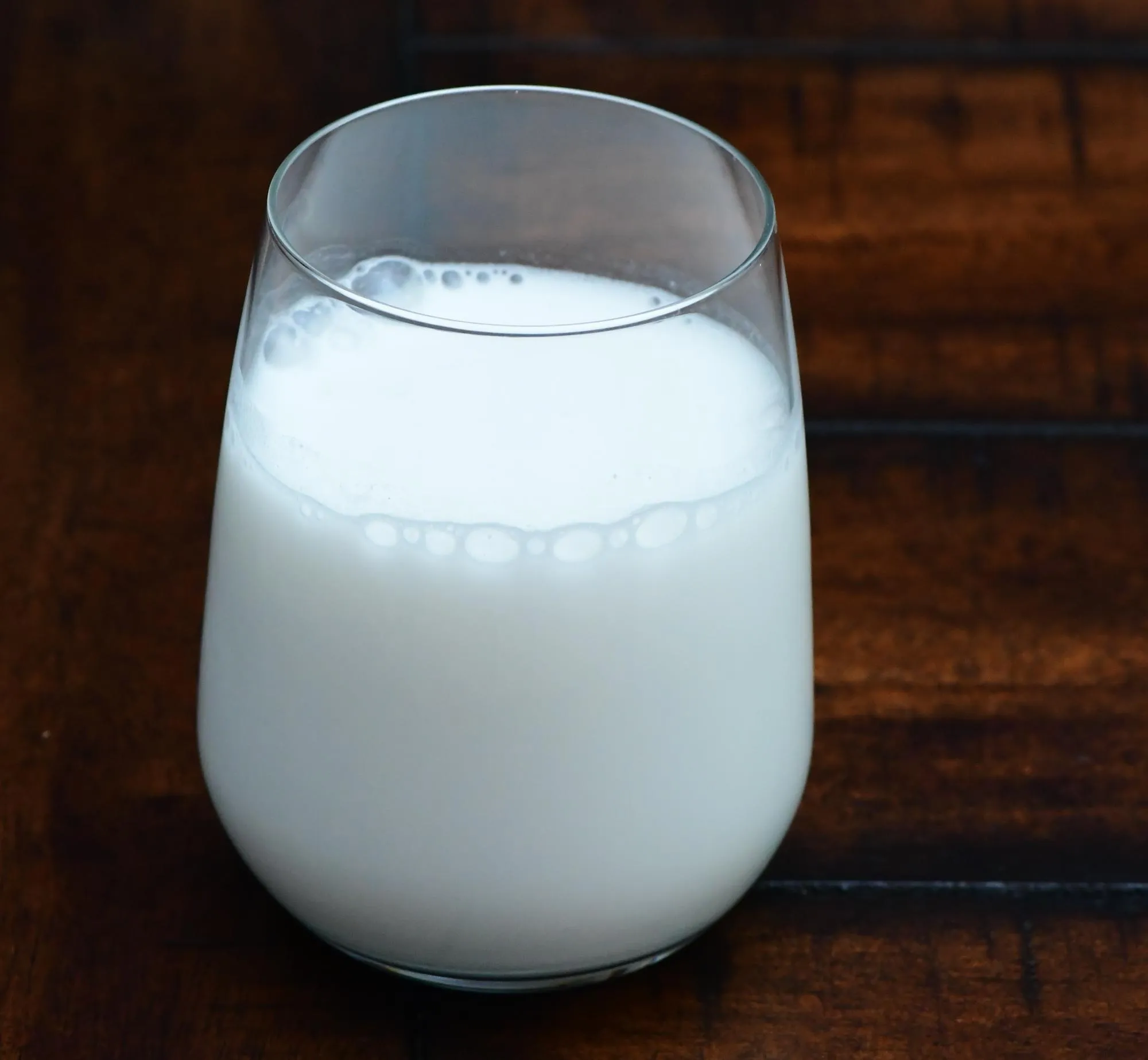 Ein Glas Milch auf einem Tisch. Milch hilft auch gegen Knoblauchatem.